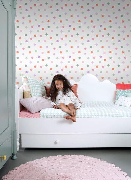 Mädchenzimmer mit weißem Bett, gemusterter Tapete und rosa Teppich