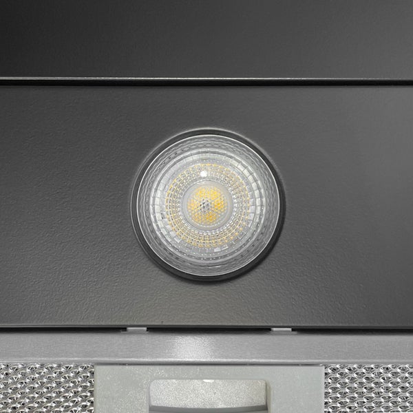 Integrierter runder LED-Strahler in einer Dunstabzugshaube über einem Metallfettfilter.