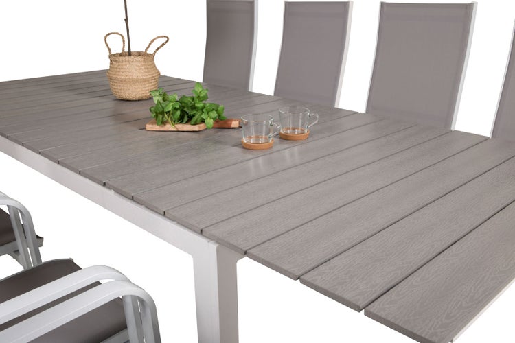 Nahaufnahme eines Gartentisches mit Stühlen, Korb, Kräutern und Tassen.