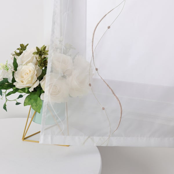 Dekoschals mit Stickerei neben Blumenarrangement