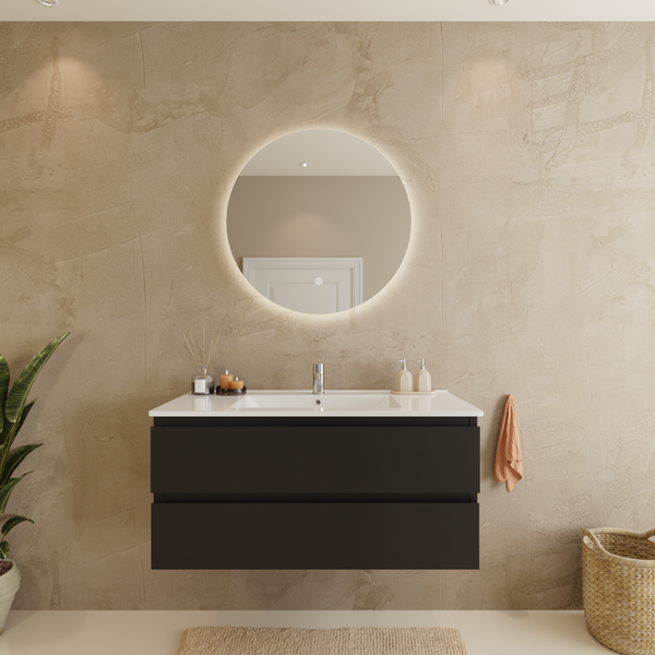 Modernes Badezimmer mit wandhängendem dunkelgrauem Waschtischunterschrank, weißem Keramikwaschbecken und rundem beleuchtetem Spiegel.
