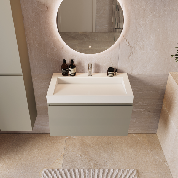 Modernes Badezimmer mit Waschtisch, wandhängendem Unterschrank, Armatur und beleuchtetem Rundspiegel vor einer Fliesenwand mit Steinoptik.