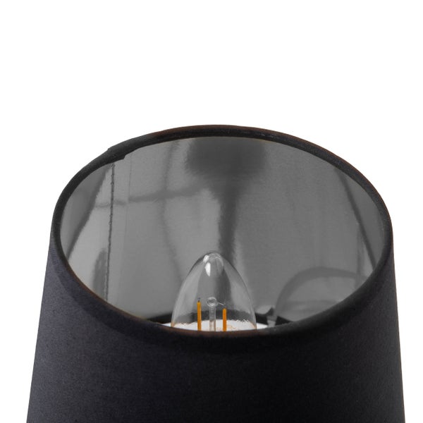 Detailaufnahme einer schwarzen Tischleuchte mit eingeschalteter Glühbirne