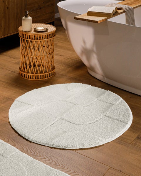 Heller runder Teppich mit geometrischem Hoch-Tief-Muster und Detailansicht der Textur.
