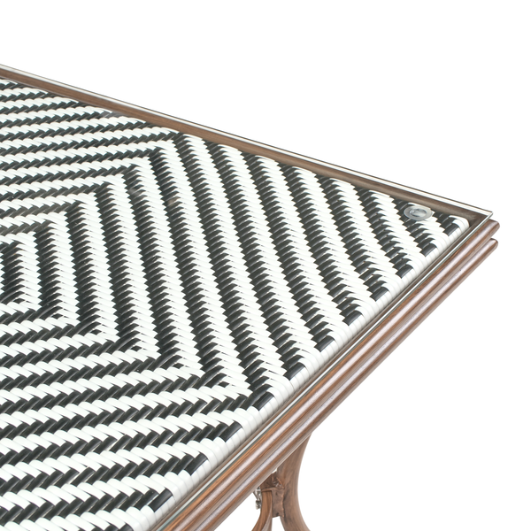 Nahaufnahme eines Bistrotisches für den Garten mit schwarz-weißem Geflecht, Glasplatte und braunem Rahmen.