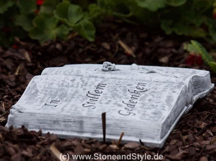 Grabschmuck in Form eines aufgeschlagenen Buches aus Stein mit der Inschrift In stillem Gedenken und einer kleinen Rosenverzierung
