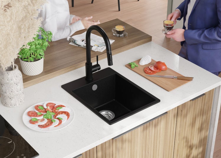 Schwarze Küchenspüle mit Armatur auf einer Küchentheke mit Lebensmitteln