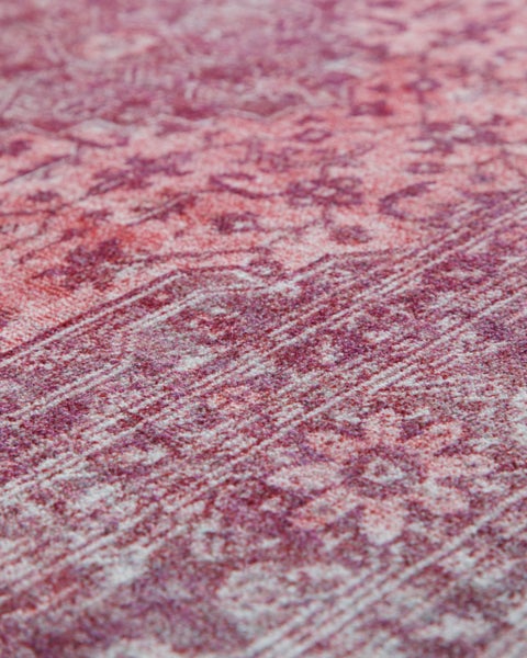 Nahaufnahme eines Teppichs mit orientalischem Muster in Rot und Rosa.