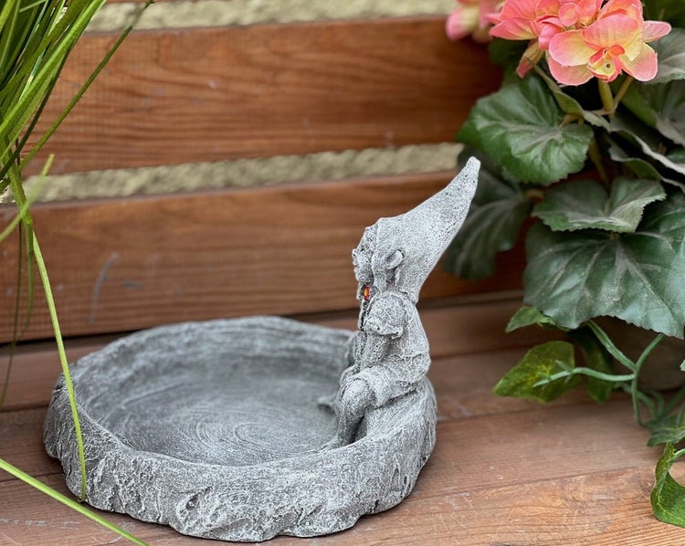 Vogeltränke in Steinoptik mit einer sitzenden Zwergenfigur für den Garten.