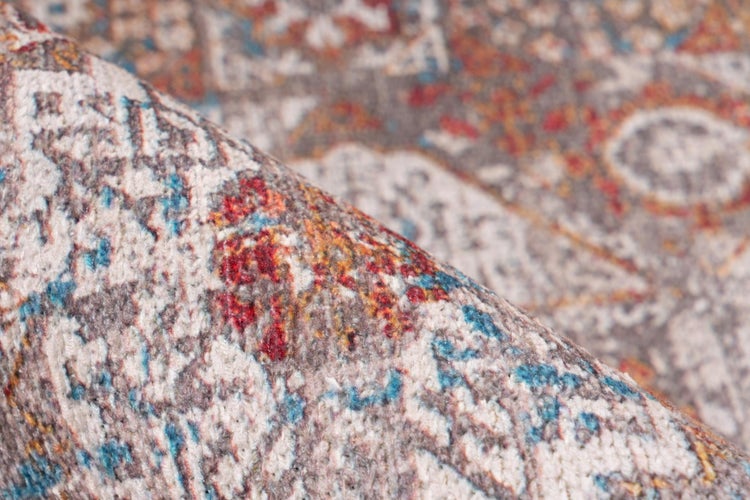 Nahaufnahme eines gemusterten Teppichs mit orientalischem Vintage Design und weichem Flor, eine umgeschlagene Ecke ist sichtbar.