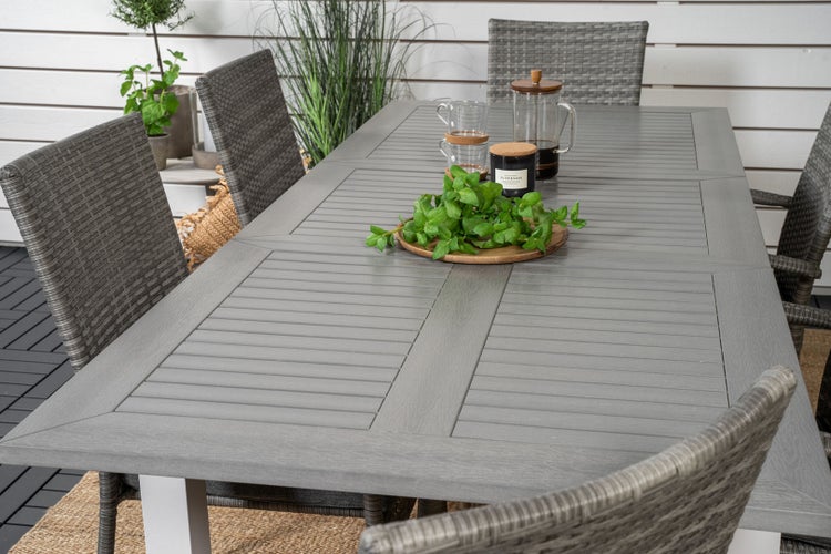 Esstisch-Set mit grauem Gartentisch und Korbsesseln im Außenbereich