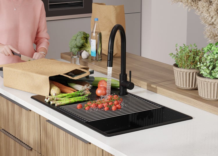 Küchenszene mit Spüle, Armatur, Gemüse und einer Person beim Kochen