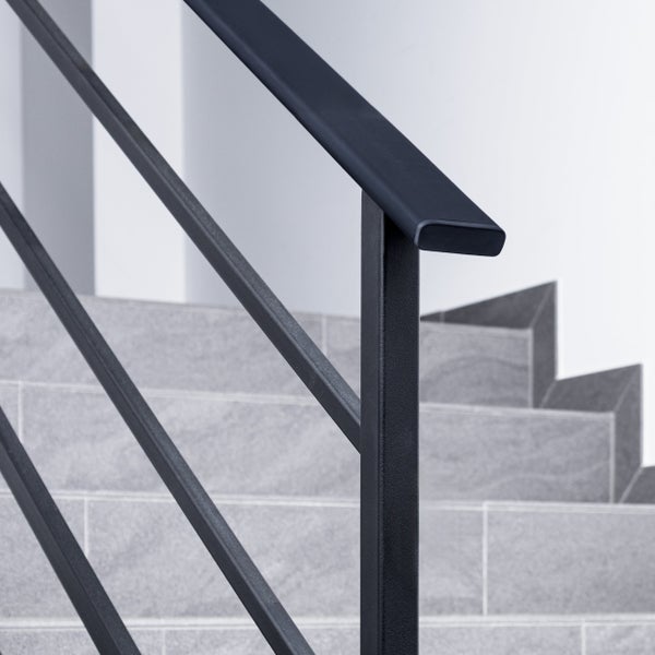 Modernes Treppengeländer aus Metall mit flachem Handlauf und diagonalen Streben an einer Steintreppe.