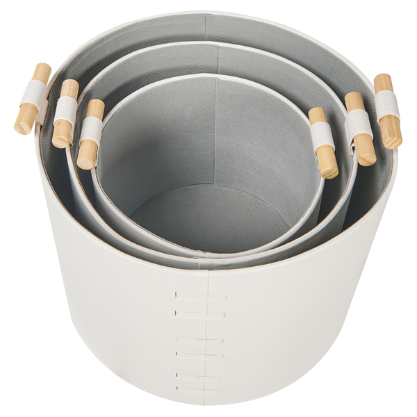 Drei weiße Aufbewahrungskörbe aus Kunstleder mit Holzgriffen ineinander gestapelt.