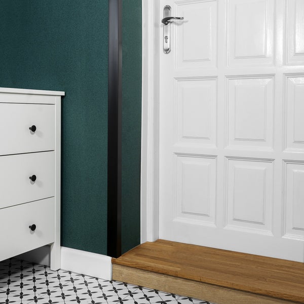 Detailaufnahme einer weißen Innentür neben einer Kommode und einer gemusterten Bodenfliese.