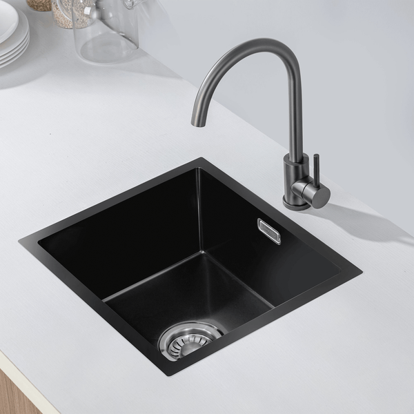 Quadratisches Einbauspüle aus Metall mit Küchenarmatur in einer hellen Arbeitsplatte