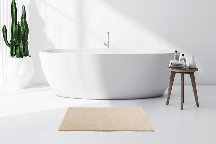 Helles, minimalistisches Badezimmer mit ovaler freistehender Badewanne, Kaktus im Topf und einer rechteckigen Badematte in Beige.