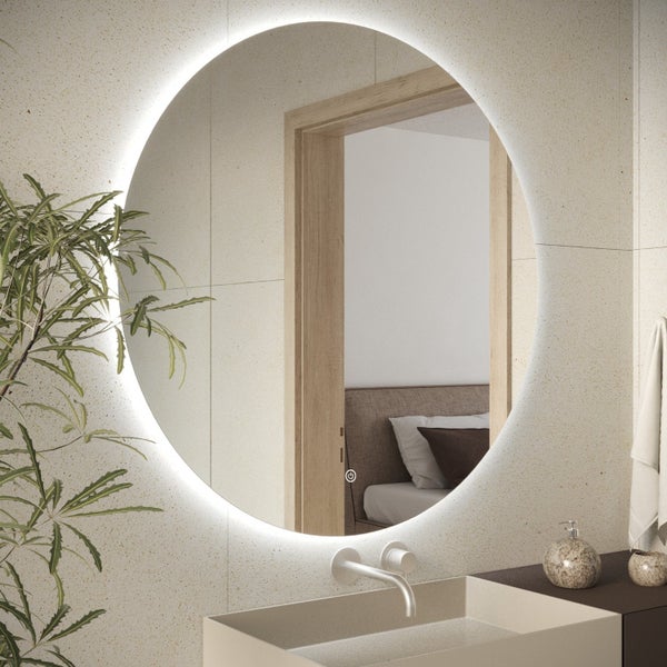 Runder Badezimmerspiegel mit integrierter LED Beleuchtung und Touch Sensor an einer gefliesten Wand mit Waschbecken und Pflanze.