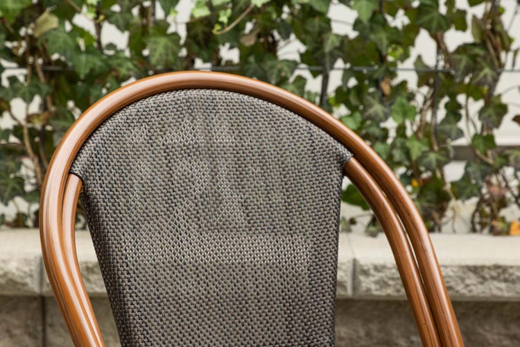 Detailansicht eines Gartenstuhls mit geflochtener Sitzfläche und Rückenlehne