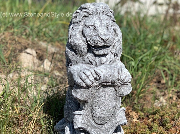 Steinerne Löwenfigur als Gartenfigur aus wetterfestem Material im Freien stehend.