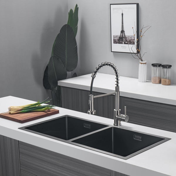 Moderne Doppelspüle aus Metall mit professioneller Küchenarmatur in einer elegant gestalteten Wohnküche mit Arbeitsplatte.