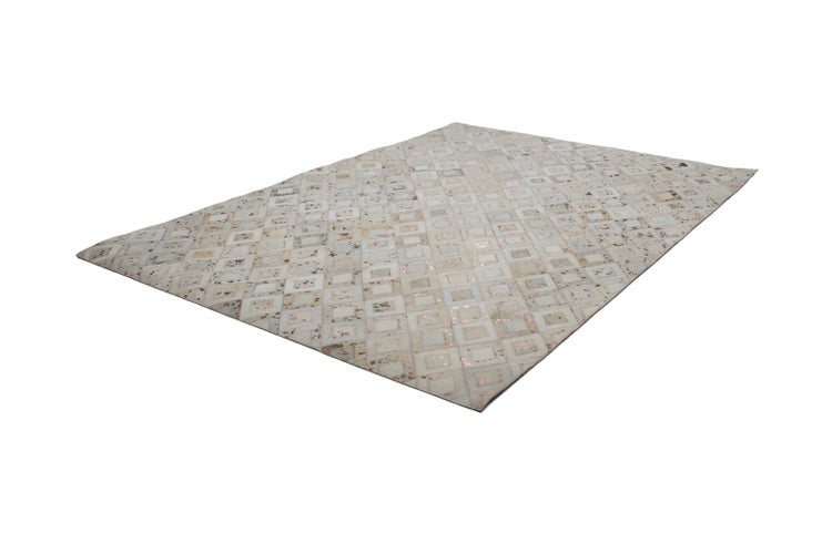 Rechteckiger Teppich aus Kuhfell-Patchwork mit geometrischem Muster.