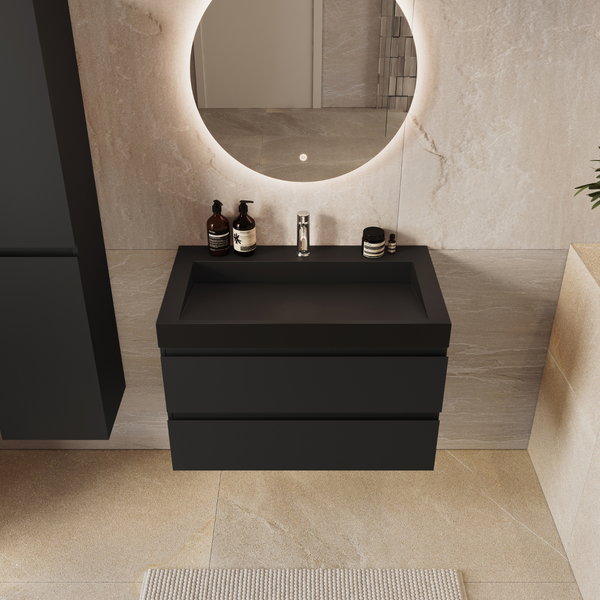 Modernes Badezimmer mit schwarzem Waschtisch, hohem Schrank, rundem LED Spiegel und beigen Steinfliesen für ein stilvolles, warmes Ambiente.