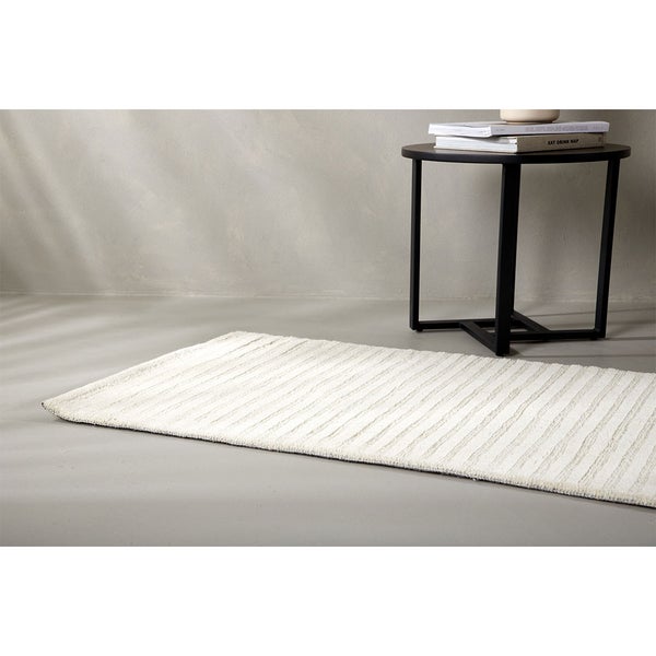 Badezimmerteppich mit gerippter Textur neben Beistelltisch
