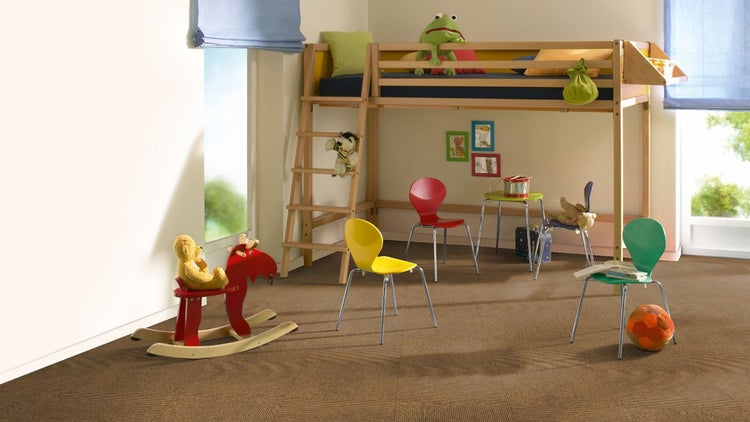 Braune Teppichfliesen in einem hellen Kinderzimmer mit Hochbett aus Holz, verschiedenen Stühlen und einem Schaukelpferd.
