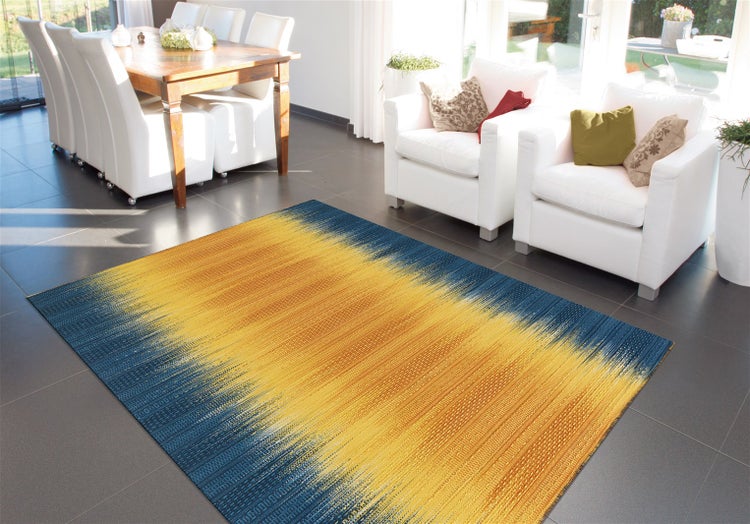 Moderner Teppich mit Farbverlauf in einem hellen, geräumigen Wohnzimmer mit Holztisch, hellen Sitzmöbeln und dunklem Fliesenboden.