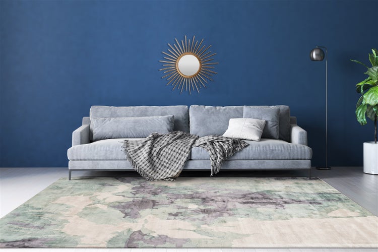 Modernes Wohnzimmer mit grauem Sofa, abstrakt gemustertem Teppich, Sonnenspiegel an einer blauen Wand und einer Stehlampe.