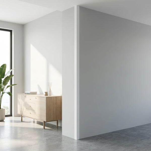 Heller moderner Wohnraum mit einer hellen Holzkommode, einer Topfpflanze und einem großen Fenster in einem minimalistisch gestalteten Raum.