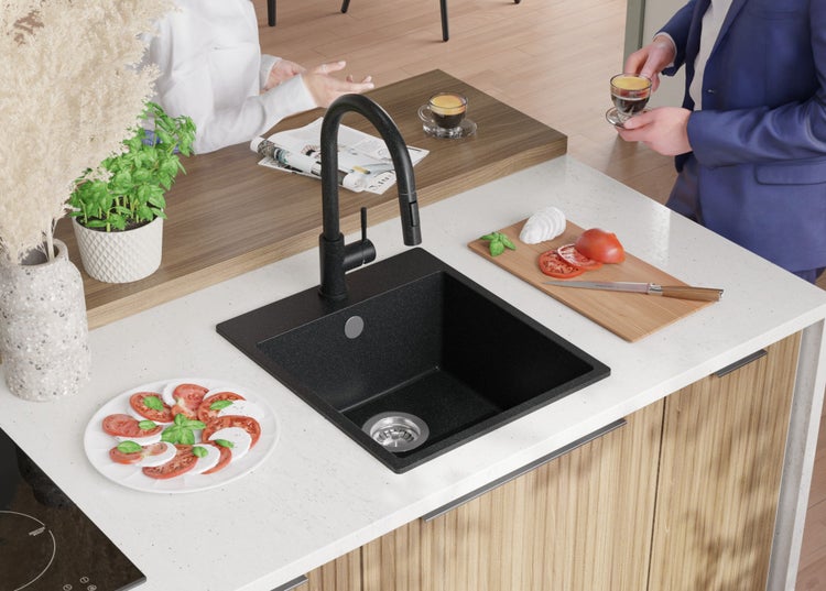 Küchenszene mit Spüle, Armatur, Arbeitsplatte mit Lebensmitteln und zwei Personen