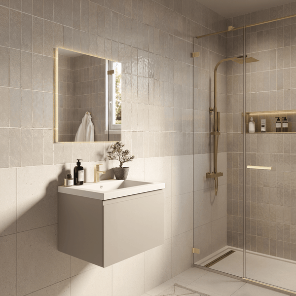 Modernes helles Badezimmer mit wandhängendem Waschtischunterschrank, weißem Waschbecken, beleuchtetem Spiegel und einer Glasdusche mit Goldarmaturen.