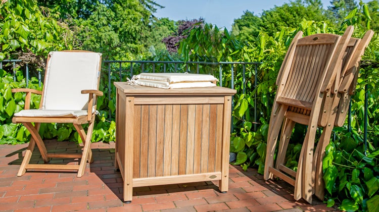 Gartenszene mit Holzstuhl, Auflagenbox und Klappstühlen auf einer Terrasse