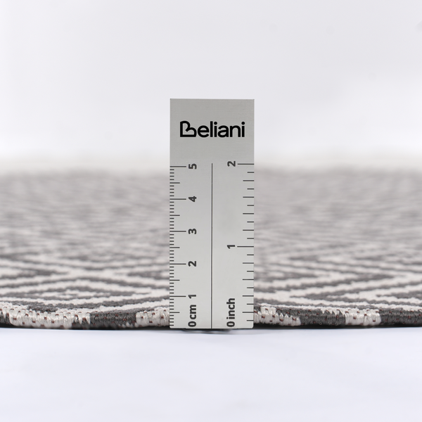 Beliani Logo auf einem Lineal, das die Florhöhe eines flachgewebten Teppichs mit geometrischem Muster misst.