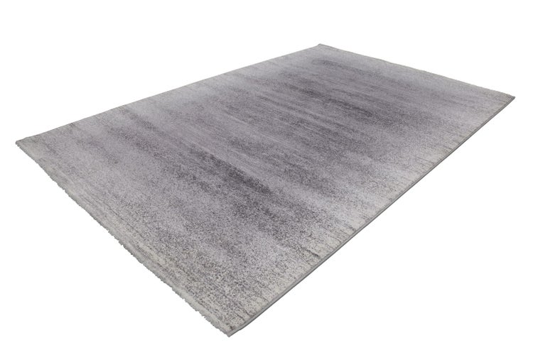 Rechteckiger Teppich mit abstraktem meliertem Muster in Grautönen.