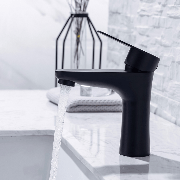 Moderne Waschtischarmatur in Schwarz mit fließendem Wasser auf einem Marmorwaschtisch in einem Badezimmer.