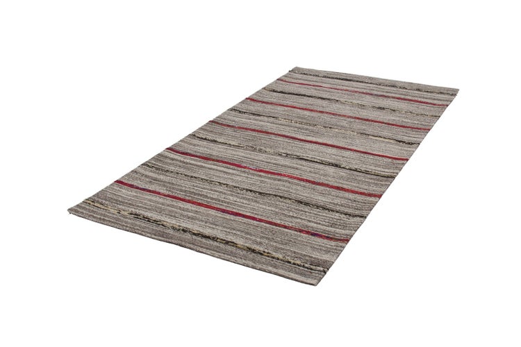 Gestreifter Kelim-Teppich in Erdtönen und Rot.