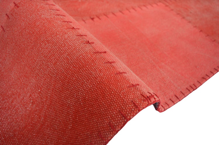 Roter flachgewebter Teppich im Patchwork-Stil mit sichtbaren Ziernähten an den Verbindungsstellen.