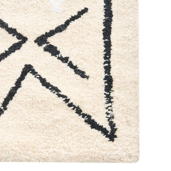 Detailansicht eines beigen Teppichs mit schwarzem, abstraktem Muster