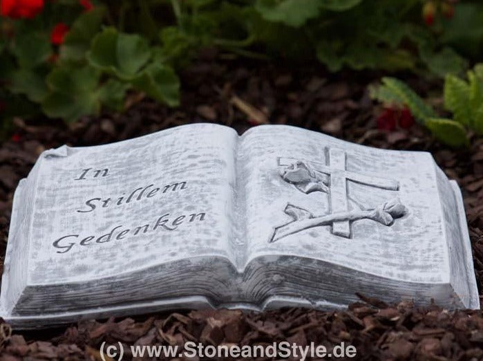 Grabschmuck in Form eines aufgeschlagenen Buches aus Stein mit der Inschrift In stillem Gedenken und einem eingearbeiteten Kreuz mit Rose
