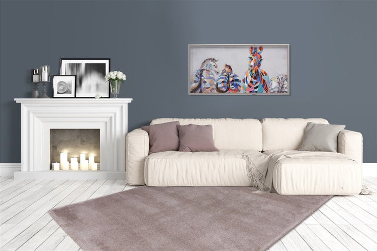 Helles Wohnzimmer mit weißem Kamin, cremefarbenem Sofa, lila Teppich und buntem Zebra-Wandbild an grauer Wand.