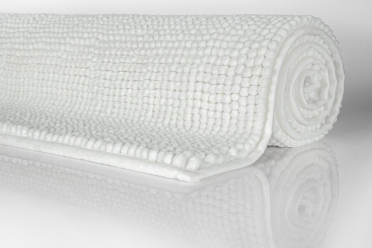Aufgerollte weiße Chenille-Badematte mit weicher, genoppter Struktur.
