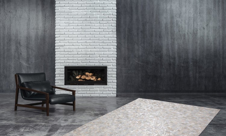 Moderner Wohnraum im Industrie-Stil mit einem hellen gemusterten Teppich auf grauem Betonboden, einem Sessel und einem weißen Backsteinkamin.