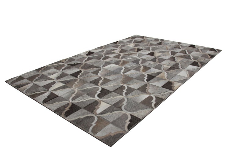 Kuhfellteppich mit geometrischem Patchwork-Muster und geschwungenen Linien.