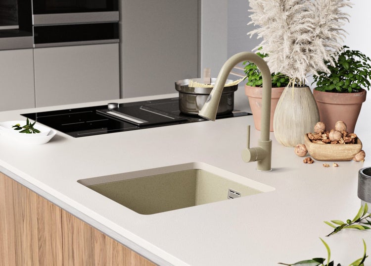 Küchenszene mit Spüle, Armatur, Kochfeld und Dekorationsartikeln auf einer Arbeitsplatte.