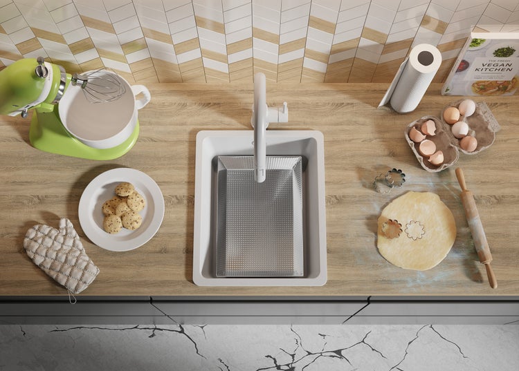 Küchenszene mit Spüle, Armatur, Mixer, Teig, Backformen, Kochbuch und Eiern.