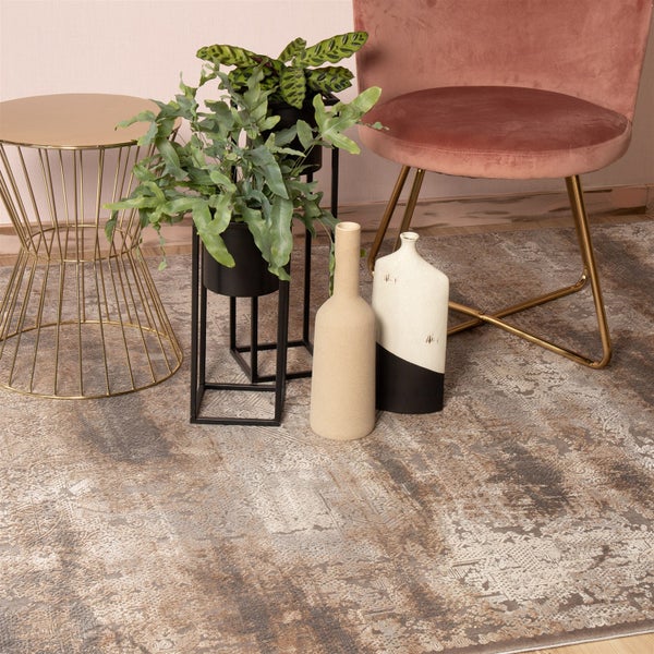 Moderner Wohnbereich mit einem Vintage-Teppich in Beige- und Brauntönen. Dazu gehören ein Beistelltisch aus Metall, Pflanzenständer und ein Samtsessel.