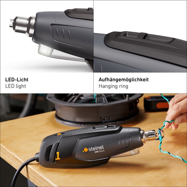 Heissluftgebläse Steinel HM Stick mit LED Licht und Aufhängering auf einem Arbeitstisch bei der Arbeit an einem Kabel.